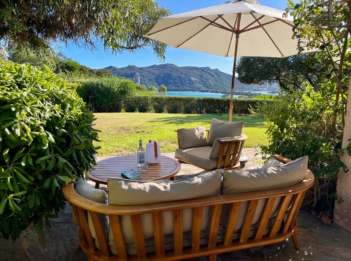 Le salon extérieur sous le parasol, face au jardin et à la baie de Santa Giulia