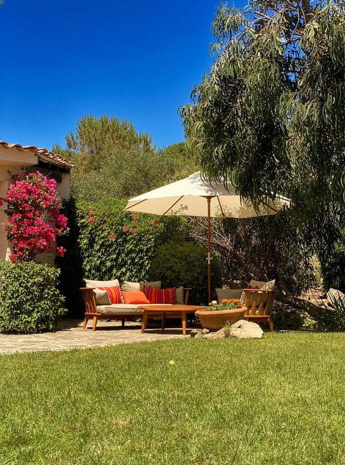 Coin salon ombragé dans le jardin, sous le parasol et à côté du bougainvillier